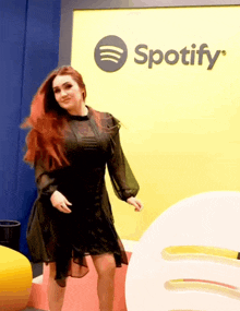 a woman is dancing in front of a sign that says spotify