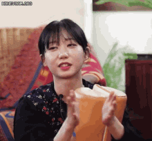 a young woman is sitting on a couch holding a drum and clapping her hands .