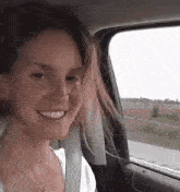 a woman is sitting in the back seat of a car smiling .