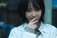 a close up of a woman covering her mouth with her finger