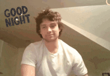 a man in a white shirt is smiling in front of a sign that says good night