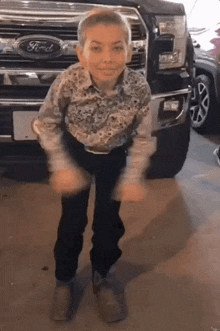 a young boy dancing in front of a ford truck