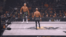 two men are standing in a wrestling ring that says all elite aw