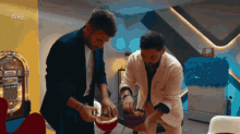 two men are cutting a cake in front of a jukebox that says rtve on it