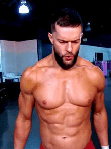 a shirtless man with a beard is standing in a room