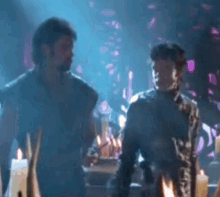 two men are standing next to each other in a room with candles and smoke coming out of it .