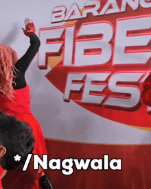 a woman in a red dress stands in front of a banner that says fibe fes