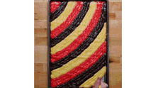 a person is spreading red yellow and black icing on a pan