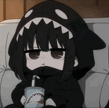 a girl wearing a shark hoodie is drinking from a cup with a straw