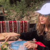 a woman wearing a hat with the letter x on it sits at a table