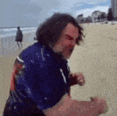 a man in a blue shirt is walking on a beach .