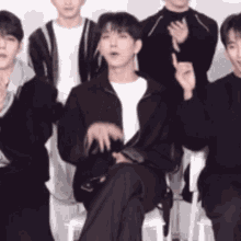 a group of young men are posing for a picture and one of them is sitting in a chair