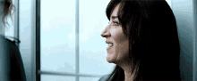 a woman is smiling and looking out a window while standing next to another woman .