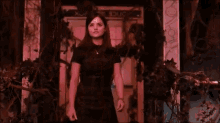 a woman in a black dress is standing in front of a police box in the dark .