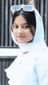 a woman wearing a white head scarf and white sunglasses
