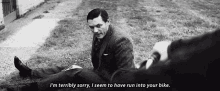 a black and white photo of a man in a suit sitting on the ground with the caption i 'm terribly sorry .