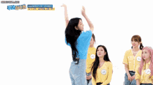 a girl in a blue shirt is dancing in front of a group of girls in yellow shirts