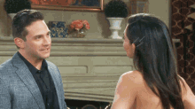 a man in a suit and a woman without a shirt are standing next to each other in front of a fireplace