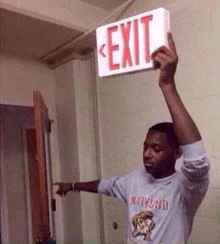 a man is holding a red exit sign above his head .