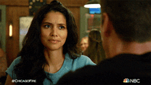 a woman in a blue shirt is looking at a man in a black shirt with nbc written on the bottom right