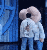 a man in a white jacket is standing next to a large stuffed animal .