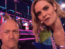 a bald man and a blonde woman are posing for a picture together