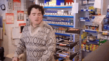 a man in a sweater stands in front of a snickers bar