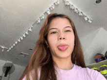 a woman sticking her tongue out in front of a ceiling with lights on it