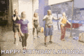 a group of people are dancing in a room with the words `` happy birthday la ronda '' written on the screen .
