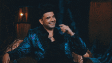 a man in a blue jacket is smiling with his hand on his face
