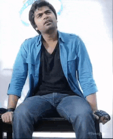 a man in a blue shirt is sitting on a chair .