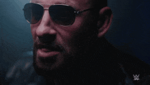a man wearing sunglasses and a leather jacket with a w logo on the bottom