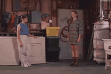 a woman is standing in a laundry room with a washing machine and dryer .