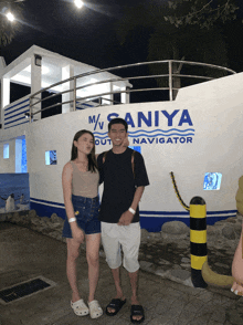 a man and a woman pose in front of a building that says m / saniya