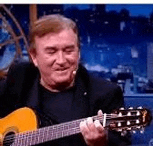 a man is playing an acoustic guitar in front of a microphone .