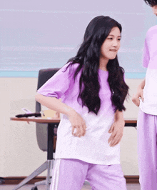 a woman in a purple shirt and purple pants is dancing with a man