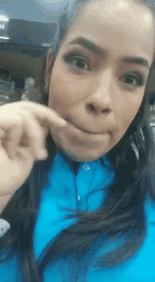 a woman wearing a blue shirt is making a face