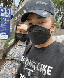 a man wearing a hat that says flight stands next to a woman wearing masks