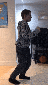 a boy wearing a fila sweatshirt is dancing in front of a map of the world