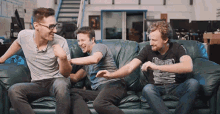 three men are sitting on a couch and one of them is wearing a shirt that says ' forest ' on it