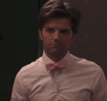 a man wearing a white shirt and a pink bow tie looks surprised