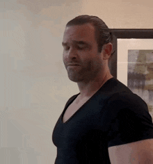 a man in a black t-shirt is standing in front of a framed picture