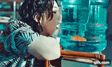 a woman is drinking water from a bottle while sitting next to a fish tank .