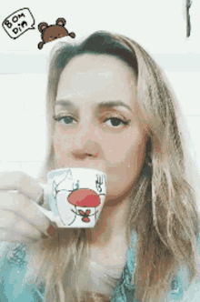 a woman drinking from a cup that says bom dia on the top