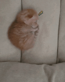 a kitten is sleeping on a white blanket with a zzz sticker on it