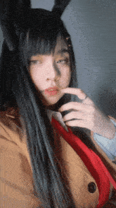a woman with long black hair and bunny ears looks at the camera