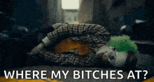a clown is laying on the ground with the words `` where my bitches at '' written above him .