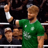 a man in a green shirt with the letter b on it is giving a thumbs up