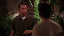 a man in a black shirt is laughing while standing next to another man in a green shirt