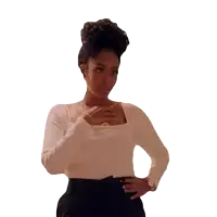 a woman wearing a white top and black pants holds her hand to her chest